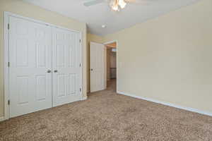 Unfurnished bedroom featuring carpet, a closet, and a ceiling fan