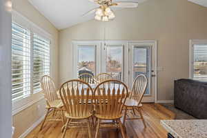 Dining space featuring hardwood / wood-style flooring, a ceiling fan, and high vaulted ceiling