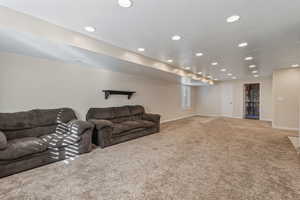 Carpeted living area with recessed lighting and baseboards