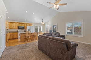 Living area with light colored carpet, vaulted ceiling, ceiling fan, and recessed lighting
