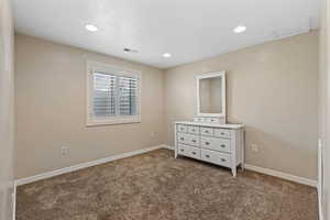 Unfurnished bedroom with dark colored carpet, recessed lighting, and attic access