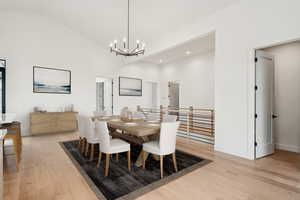 Dining area featuring light wood-type flooring, recessed lighting, lofted ceiling, and a chandelier