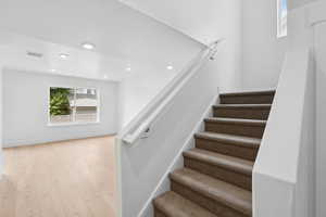 Stairway with wood finished floors and recessed lighting