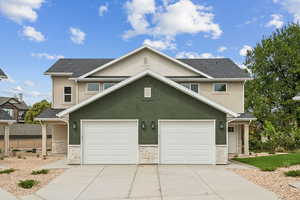 Traditional home featuring stone siding, stucco siding, driveway, and a garage