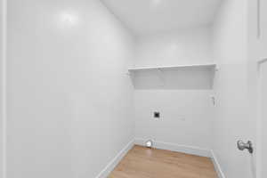 Laundry area with light wood-type flooring, hookup for an electric dryer, and hookup for a washing machine
