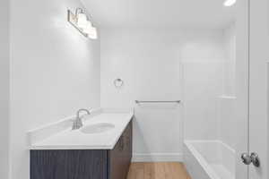Bathroom with vanity, light wood finished floors, and bathtub / shower combination