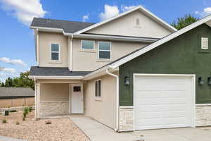 Traditional-style home featuring stone siding, stucco siding, roof with shingles, and a garage