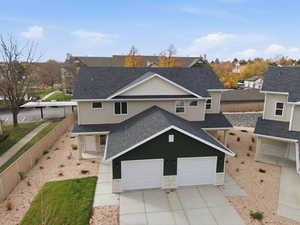 Traditional home featuring roof with shingles, stucco siding, a residential view, concrete driveway, and a garage