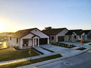 Modern farmhouse featuring concrete driveway, board and batten siding, a garage, stone siding, and a lawn
