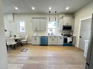 Kitchen featuring light wood-style floors, appliances with stainless steel finishes, healthy amount of natural light, recessed lighting, and a textured ceiling