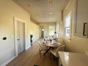 Dining space featuring light wood-style floors, recessed lighting, and a textured ceiling