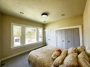 Carpeted bedroom featuring a closet, a textured ceiling, and recessed lighting