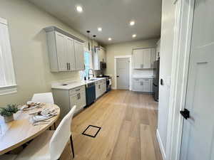 Kitchen featuring gray cabinets, light wood-type flooring, recessed lighting, stainless steel appliances, and hanging light fixtures