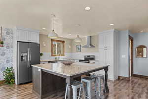 Kitchen featuring stainless steel appliances, light stone countertops, a kitchen breakfast bar, dark wood-style floors, and a textured ceiling