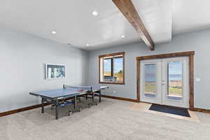 Recreation room with beamed ceiling, light carpet, a textured ceiling, recessed lighting, and french doors