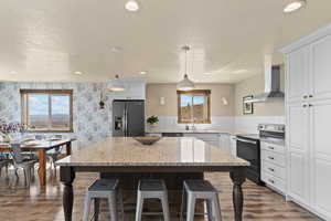 Kitchen featuring stainless steel appliances, a kitchen breakfast bar, pendant lighting, dark wood-style floors, and white cabinets