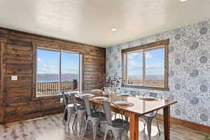 Dining area with wallpapered walls, wood finished floors, a textured ceiling, a water and mountain view, and recessed lighting