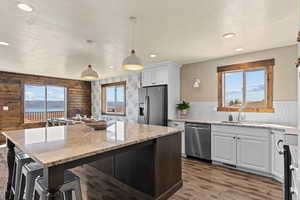 Kitchen with appliances with stainless steel finishes, plenty of natural light, light stone countertops, pendant lighting, and a textured ceiling