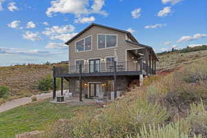 Back of house featuring stone siding, french doors, a patio, and a wooden deck