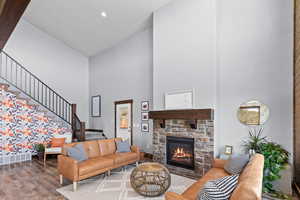 Living room with a towering ceiling, stairs, wood finished floors, and a fireplace