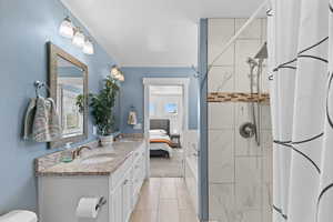Ensuite bathroom featuring a shower stall, double vanity, and light tile patterned floors