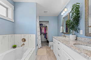 Full bath with a bath, a spacious closet, and double vanity
