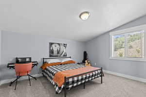 Bedroom with light colored carpet and a textured ceiling