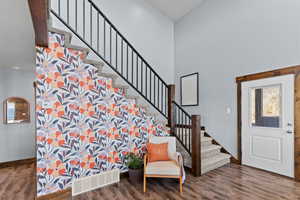 Foyer entrance with stairs, dark wood-style flooring, and a high ceiling