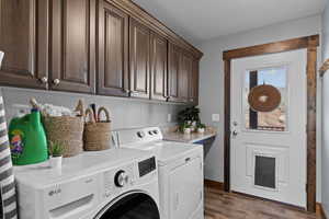 Washroom featuring dark wood-type flooring, a textured ceiling, independent washer and dryer, and cabinet space