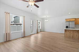 Unfurnished living room with plenty of natural light, ceiling fan, light wood-style floors, a chandelier, and recessed lighting