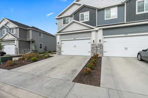 View of front of house featuring board and batten siding, driveway, stone siding, and a garage