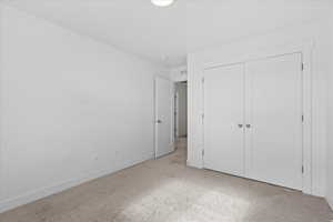 Unfurnished bedroom with light colored carpet and a closet