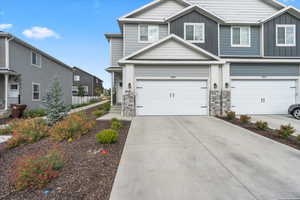 View of front of house with board and batten siding, concrete driveway, a garage, and stone siding