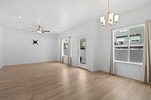 Unfurnished dining area featuring plenty of natural light, recessed lighting, light wood finished floors, ceiling fan, and a chandelier