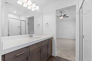 Full bathroom featuring vanity, dark wood-style floors, a stall shower, and a ceiling fan