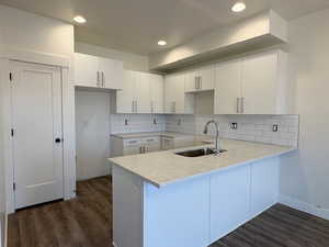 Kitchen with white cabinetry, a peninsula, dark wood-type flooring, decorative backsplash, and recessed lighting