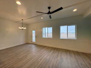Unfurnished room with a ceiling fan, light wood finished floors, plenty of natural light, and hanging lights