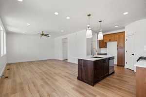Kitchen with decorative light fixtures, recessed lighting, light wood-style floors, a kitchen island with sink, and open floor plan