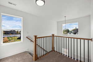 Staircase with carpet floors, a chandelier, and a residential view