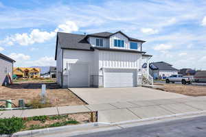 View of front facade with board and batten siding, driveway, a residential view, roof with shingles, and a garage