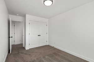 Unfurnished bedroom with dark carpet and a closet