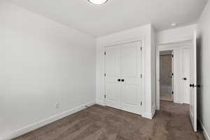 Unfurnished bedroom with dark colored carpet and a closet
