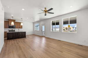 Kitchen featuring open floor plan, hanging light fixtures, a center island with sink, recessed lighting, and tasteful backsplash