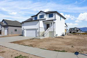 View of front facade featuring board and batten siding, driveway, an attached garage, a mountain view, and stone siding