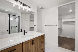 Full bathroom featuring a spacious closet, a stall shower, vanity, light marble finish floors, and recessed lighting