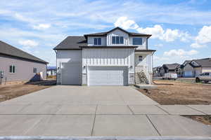View of front facade with board and batten siding, concrete driveway, stone siding, a porch, and stairway