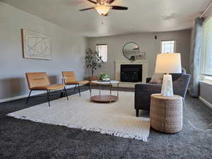 Carpeted living room with a fireplace and a ceiling fan