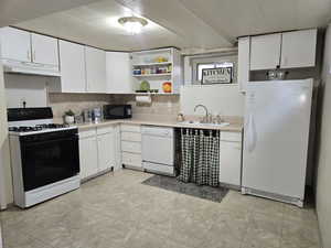 Kitchen featuring white appliances, light countertops, open shelves, under cabinet range hood, and white cabinets