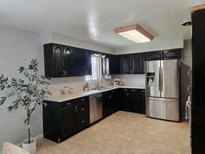 Kitchen featuring dark cabinetry, appliances with stainless steel finishes, and light countertops
