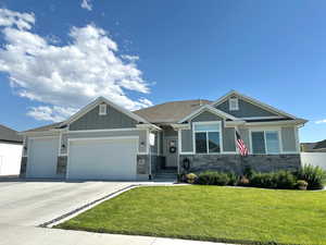 Craftsman house with board and batten siding, a garage, and stone siding